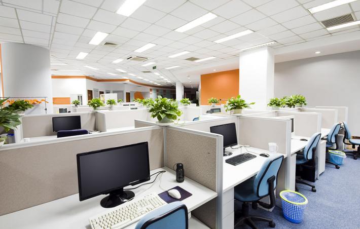 photo of an office with various cubbies with empty chairs and monitors