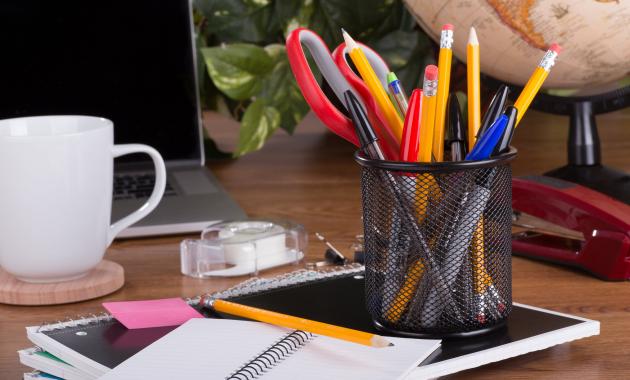 a desk with office supplies and a laptop on top