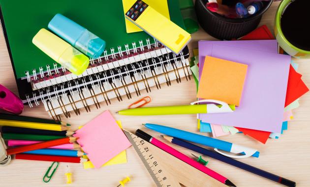 photo of a desk littered with notebooks, pencils, post-it notes and paper